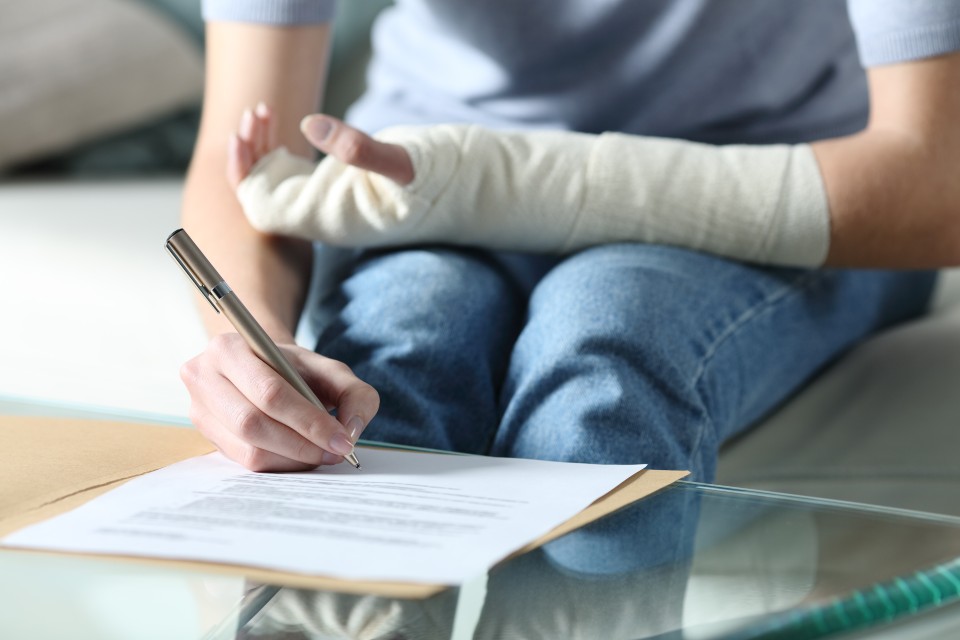 Persona con un brazo vendado firma un documento